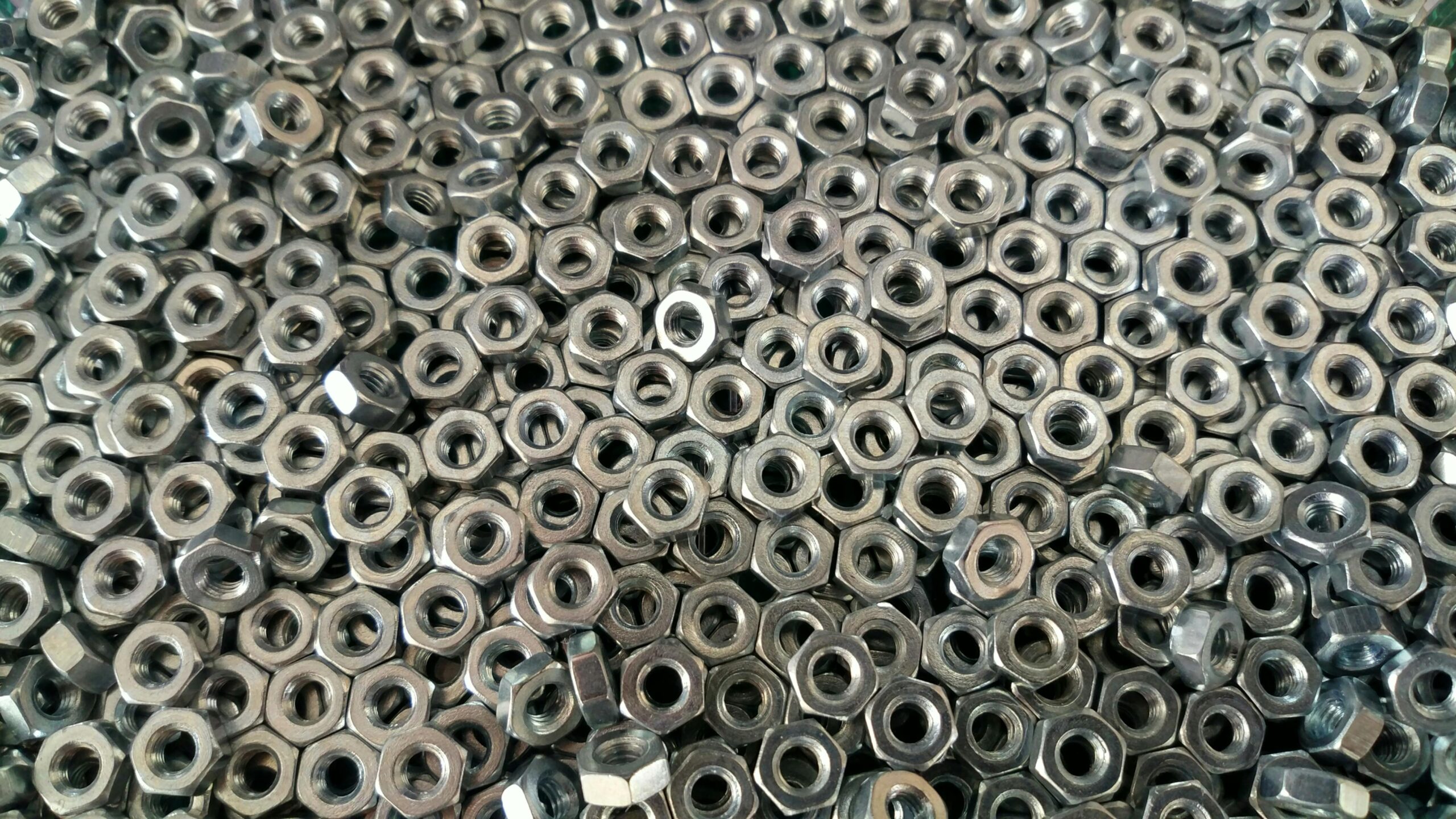 Detail of numerous stainless steel nuts creating an industrial texture.